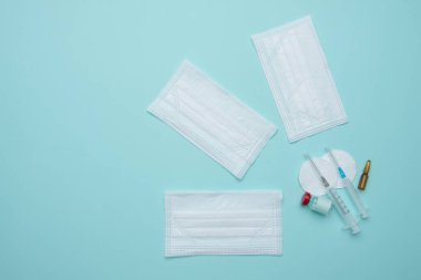 Şırınga, maske, mavi arka planda ampul, aşı konsepti.