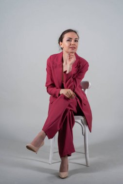 Full length photo of attractive chic business lady sit chair wear red suit high-heels isolated grey background clipart