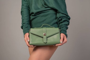 Stüdyoda zümrüt kazakla poz veren güzel bir genç kadın.