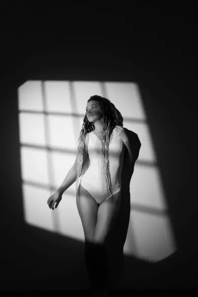 stock image Lonely woman in white bodysuit posing against the wall