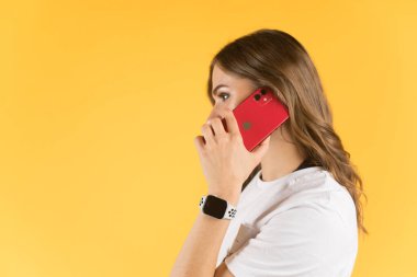 Tula, Rusya - 23 Eylül 2020: Yeni model iPhone ve elma saatiyle akıllı telefondan konuşan güzel genç kadın.