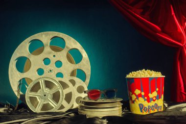 Eski film makaraları, patlamış mısır ve masada 3D bardaklar. Gözlüklere odaklan. Çok renkli bir arka plan. Evolution Film Ortamı