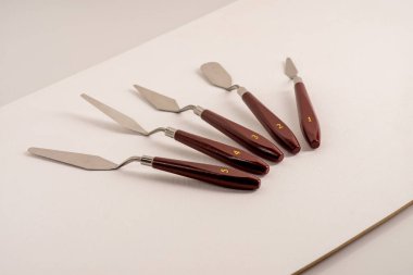 Beyaz bir sanat tuvalinde beş palet bıçağı var..