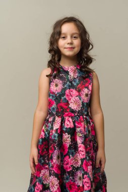 Gri arka planda izole edilmiş gülümseyen küçük kız çocuğunun fotoğrafı. Kameraya bak.