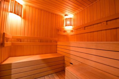 Sauna odasında otur. Taş ısıtıcılı boş ahşap buhar odası. Sağlıklı olmak için sauna odası. Sauna odası ve geleneksel sauna aksesuarları. Sağlıklı ve spa tarzı..