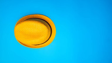 Mavi arka planda hasır şapkanın üst görüntüsü. Yukardan aşağıya doğru düz bir kompozisyon. Hasır şapkanın fotokopi alanı olan minimalist düz yatay fotoğrafı.