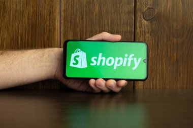 Kyoto Şehri, Japonya - 31 Temmuz 2023: Ahşap arka planda Shopify logosu olan Apple iPhone