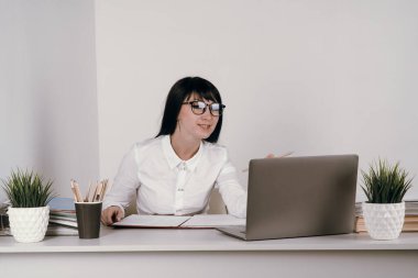 Evde bilgisayarla çalışan mutlu ve serbest bir genç kadın. Çevrimiçi öğrenim gören çekici iş kadını, dizüstü bilgisayar, web sörfü bilgileri veya internet mağazasından alışveriş yapıyor..