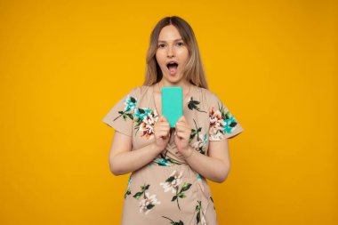 Pozitif neşeli kızın portresi akıllı telefon paylaşımı sosyal medya haber paylaşımı giyim tarzı moda elbise sarı arkaplan üzerinde izole