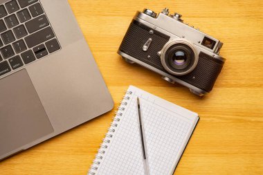 Üst görünüm ofis fotoğraf masası, dizüstü bilgisayarı, defteri, kamerası ve kalemi var..
