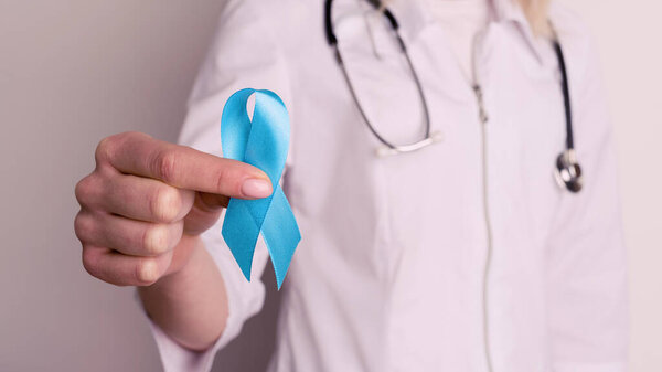 Female doctor holding a blue ribbon in her hands - image