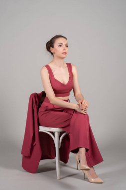 Çekici iş kadınının tam boy fotoğrafı. Koltuğa otur. Kırmızı giyin.