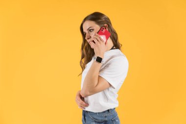 Tula, Russia - September 23,2020: Beautiful young woman with new model iphone and apple watch talking on smartphone.