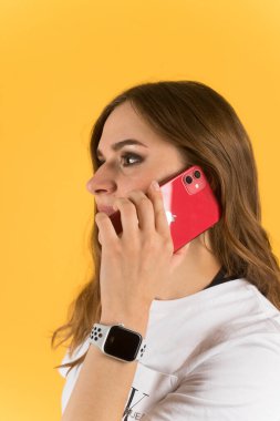 Tula, Rusya - 23 Eylül 2020: Yeni model iPhone ve elma saatiyle akıllı telefondan konuşan güzel genç kadın.