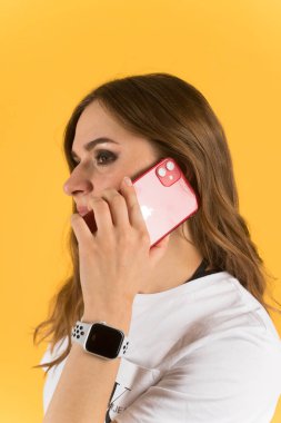 Tula, Rusya - 23 Eylül 2020: Yeni model iPhone ve elma saatiyle akıllı telefondan konuşan güzel genç kadın.