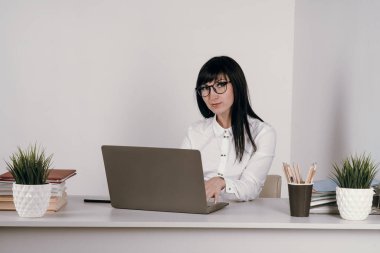 Evde bilgisayarla çalışan mutlu ve serbest bir genç kadın. Çevrimiçi öğrenim gören çekici iş kadını, dizüstü bilgisayar, web sörfü bilgileri veya internet mağazasından alışveriş yapıyor..