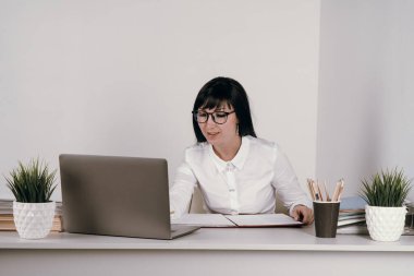 Evde bilgisayarla çalışan mutlu ve serbest bir genç kadın. Çevrimiçi öğrenim gören çekici iş kadını, dizüstü bilgisayar, web sörfü bilgileri veya internet mağazasından alışveriş yapıyor..