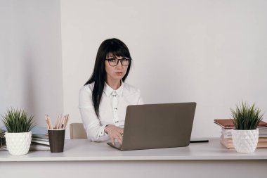 Evde bilgisayarla çalışan mutlu ve serbest bir genç kadın. Çevrimiçi öğrenim gören çekici iş kadını, dizüstü bilgisayar, web sörfü bilgileri veya internet mağazasından alışveriş yapıyor..