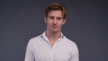 Yakışıklı, kendine güvenen, kızıl saçlı, beyaz gömlekli ve gülümseyen bir adam..