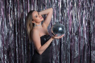 Aynalı disko topu parıltılı perde arkaplanlı çekici giyinen sevimli narsist kadının fotoğrafı.