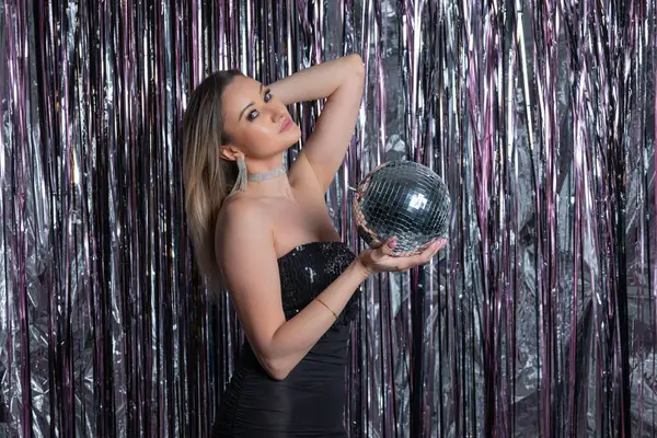 Aynalı disko topu parıltılı perde arkaplanlı çekici giyinen sevimli narsist kadının fotoğrafı.