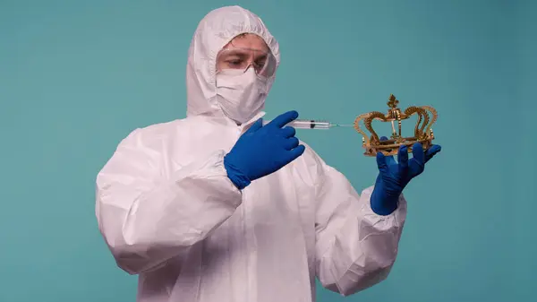 Stock image A male doctor in protective overalls and a mask makes an injection in the crown. Coronovirus protection concept in China. - image