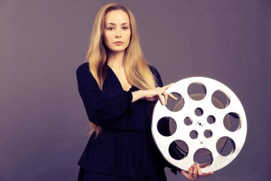 A young woman movie executive is holding an old film reel clipart