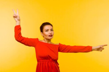 Kırmızı elbiseli güzel bir kadın sarı arka planı işaret ediyor.
