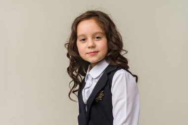 Gri arka planda izole edilmiş gülümseyen küçük kız çocuğunun fotoğrafı. Kameraya bak.