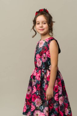 Gri arka planda izole edilmiş gülümseyen küçük kız çocuğunun fotoğrafı. Kameraya bak.