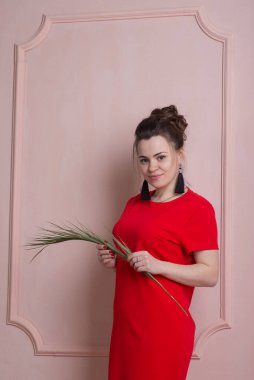 Rokoko tarzında kırmızı elbiseli güzel bir kadın duvara poz veriyor.