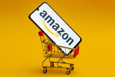 Kyoto Şehri, Japonya - 12 Ağustos 2024: Amazon logosu akıllı telefon ekranında sarı arka plandaki oyuncak market arabasında.