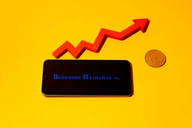 Kyoto Şehri, Japonya - 22 Ağustos 2024: Berkshire Hathaway logosu akıllı telefon ekranında ve kırmızı çizelge okunda sarı arka planda bitcoin yakınında.
