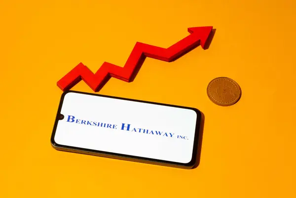 stock image Kyoto city, Japan - august 22, 2024: Berkshire Hathaway logo on the smartphone screen and red chart arrow near bitcoin coin on yellow background.