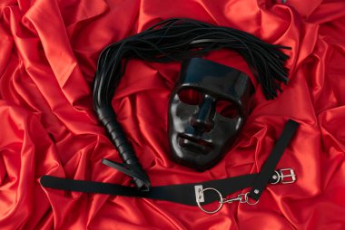 Yetişkin seks oyunları. Sapıkça bir yaşam tarzı. Kırmızı çarşafların üzerindeki kırbaçlama ve maske. Bdsm kıyafeti