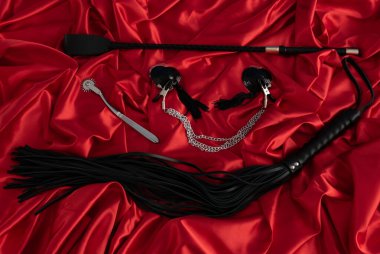 Yetişkin seks oyunları. Sapıkça bir yaşam tarzı. Kırmızı çarşafların üzerinde kırbaç ve kırbaç izleri var. Bdsm kıyafeti