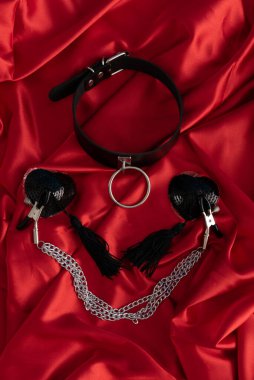 Yetişkin seks oyunları. Sapıkça bir yaşam tarzı. Kırmızı çarşafta tasma var. Bdsm kıyafeti