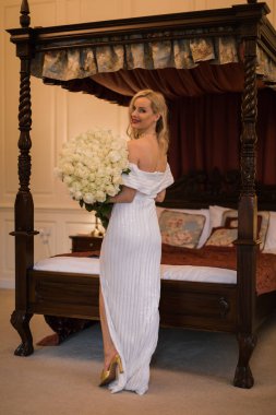 Elegant charming young blonde bride  in a wedding dress with a b