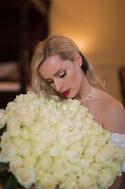 Elegant charming young blonde bride  in a wedding dress with a b
