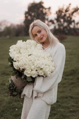 Portrait of beautiful young blonde woman in park  with bouquet o