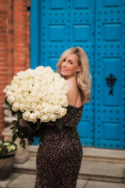 Blonde happy woman in dress  holding big bouquet white flowers r