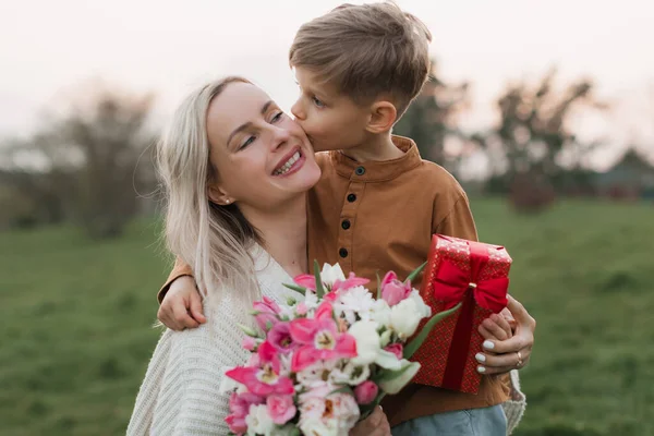 cute baby (son) gives a gift box and bouquet of flower to his be