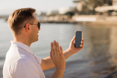 happy man on holiday relax walk along the beach use phone online