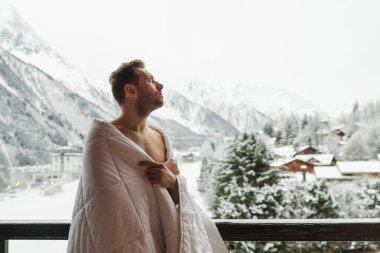 Happy bearded handsome man with beard is standing on balcony cov