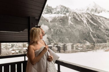 a couple of men and women standing on balcony covered in blanket