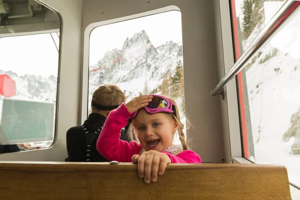Little girl looking to camera in train during travel on cogwheel