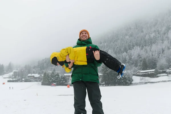 Father lifting  son up while having fun together outdoor on snow