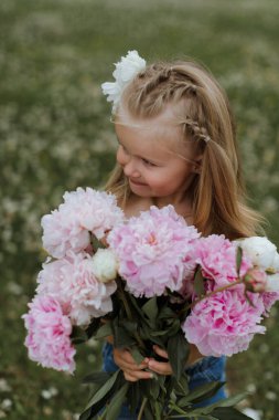 Beautiful little girl with big peonies bouquet. Spring blossom a