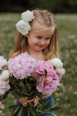 Happy Beautiful little girl with big peonies bouquet. Spring blo