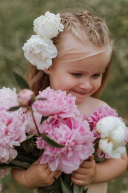 Happy Beautiful little girl with big peonies bouquet. Spring blo